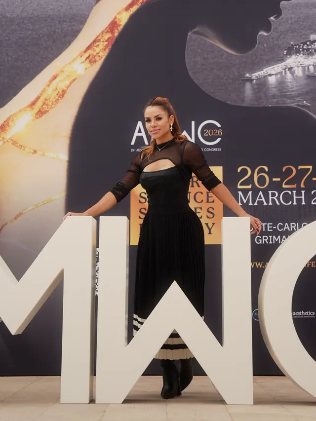 Dra. Tatiane Rodrigues diante do painel do congresso AMWC, em Monte-Carlo